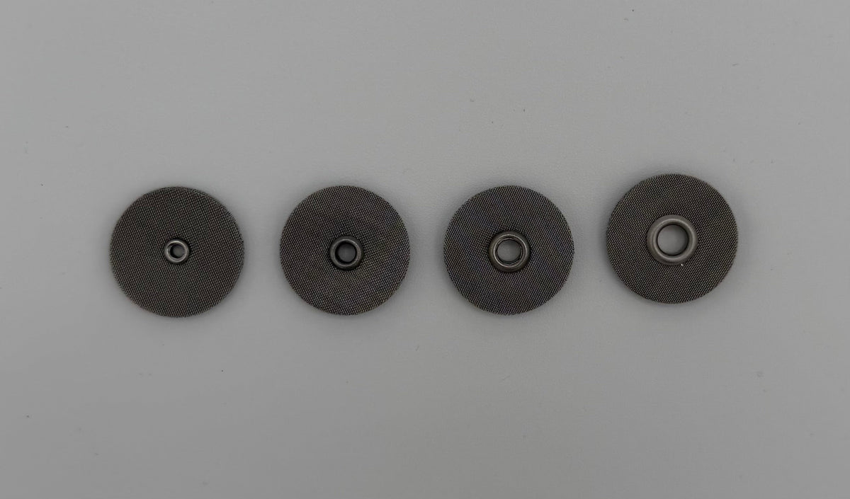 Four round stainless steel welding cup screens with central holes on a light background
